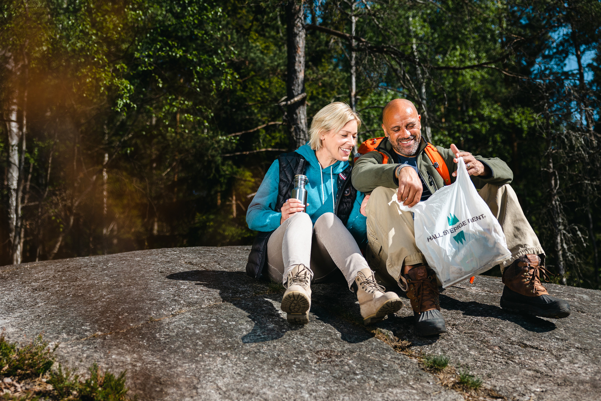 En kvinna och man sitter i naturen och har plockat skräp