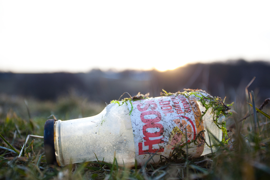 Skräpig glasflaska som ligger i naturen